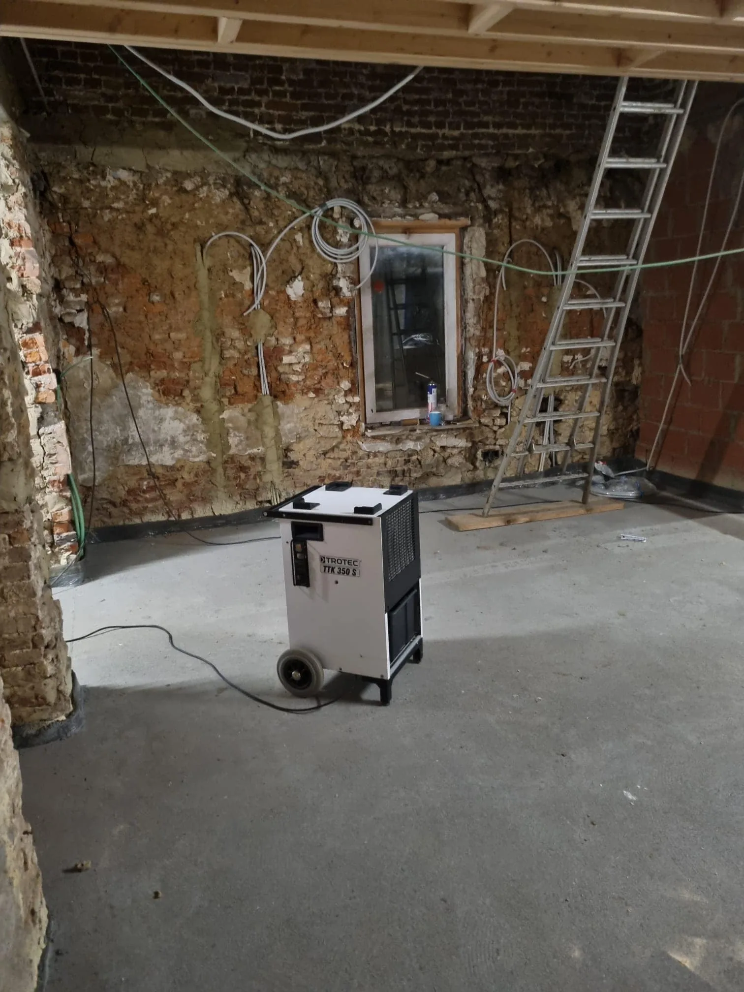 Déshumidificateur Trotec TTK350S installé sur un chantier de rénovation aux murs décapés